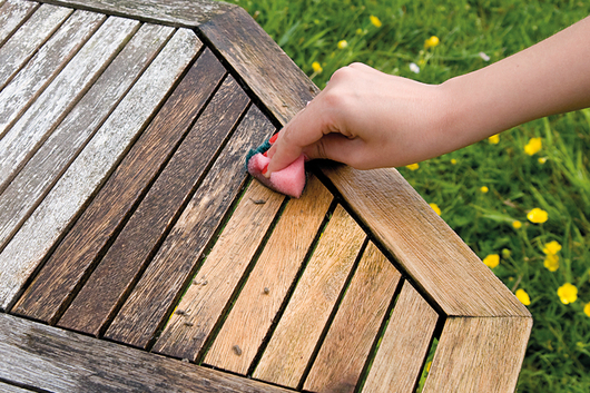 Das vergraute Holz eines Gartentischs wird mit Hilfe von biopin-Produkten wieder aufgehellt.