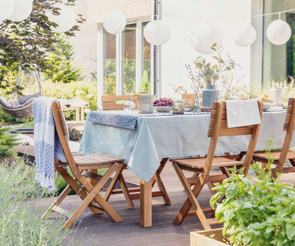 Holzstühle und ein schön gedeckter Tisch stehen im Garten.